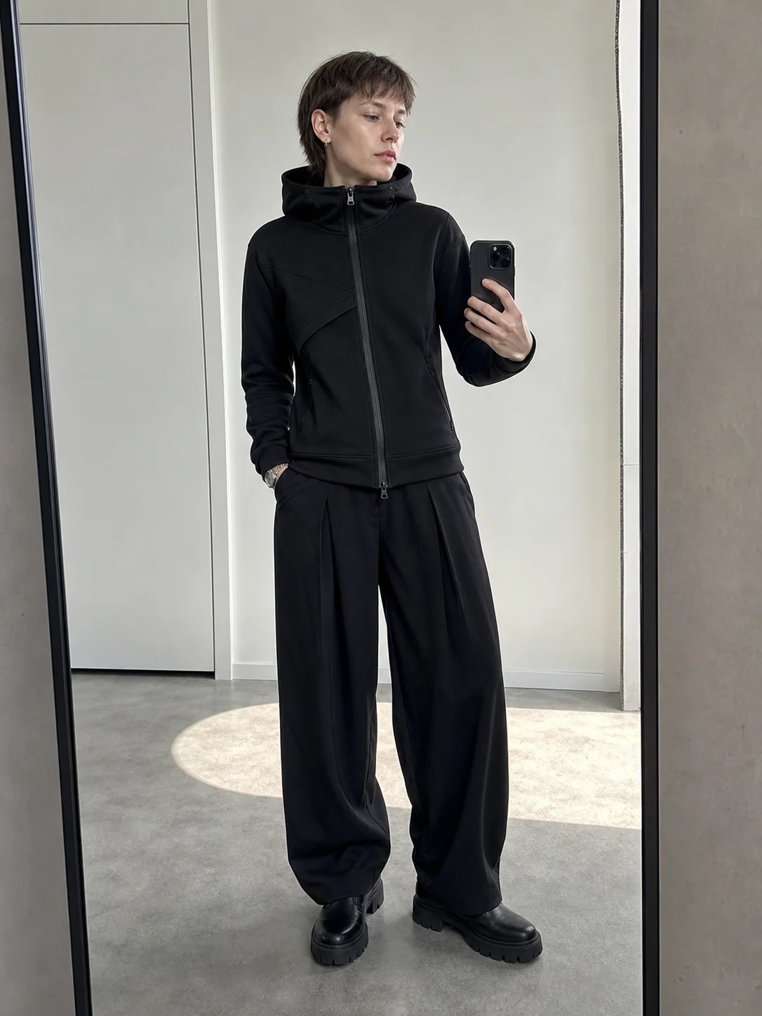 Berlin apartment mirror styling image showing the Clothixpack CXP-H107 Arc Zip Hoodie with black pleated wide-leg trousers.