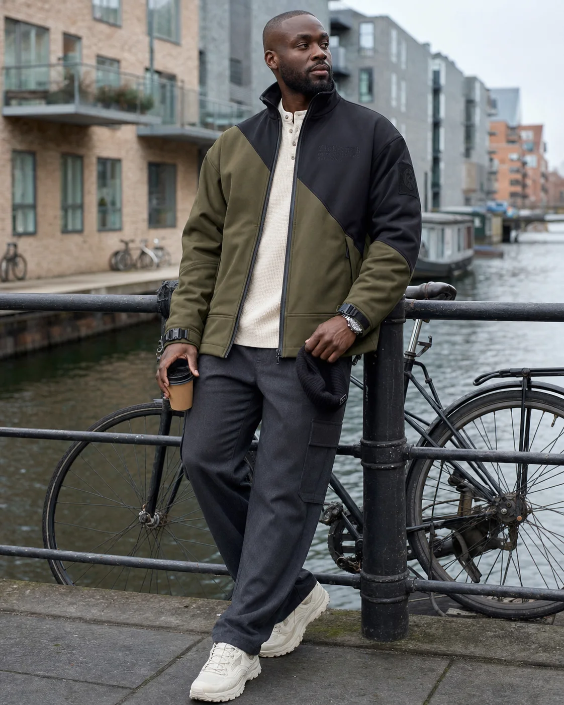 Copenhagen canal styling image showing the Clothixpack CXP-J106 Spire Softshell Jacket with charcoal cargos and off-white trail sneakers.